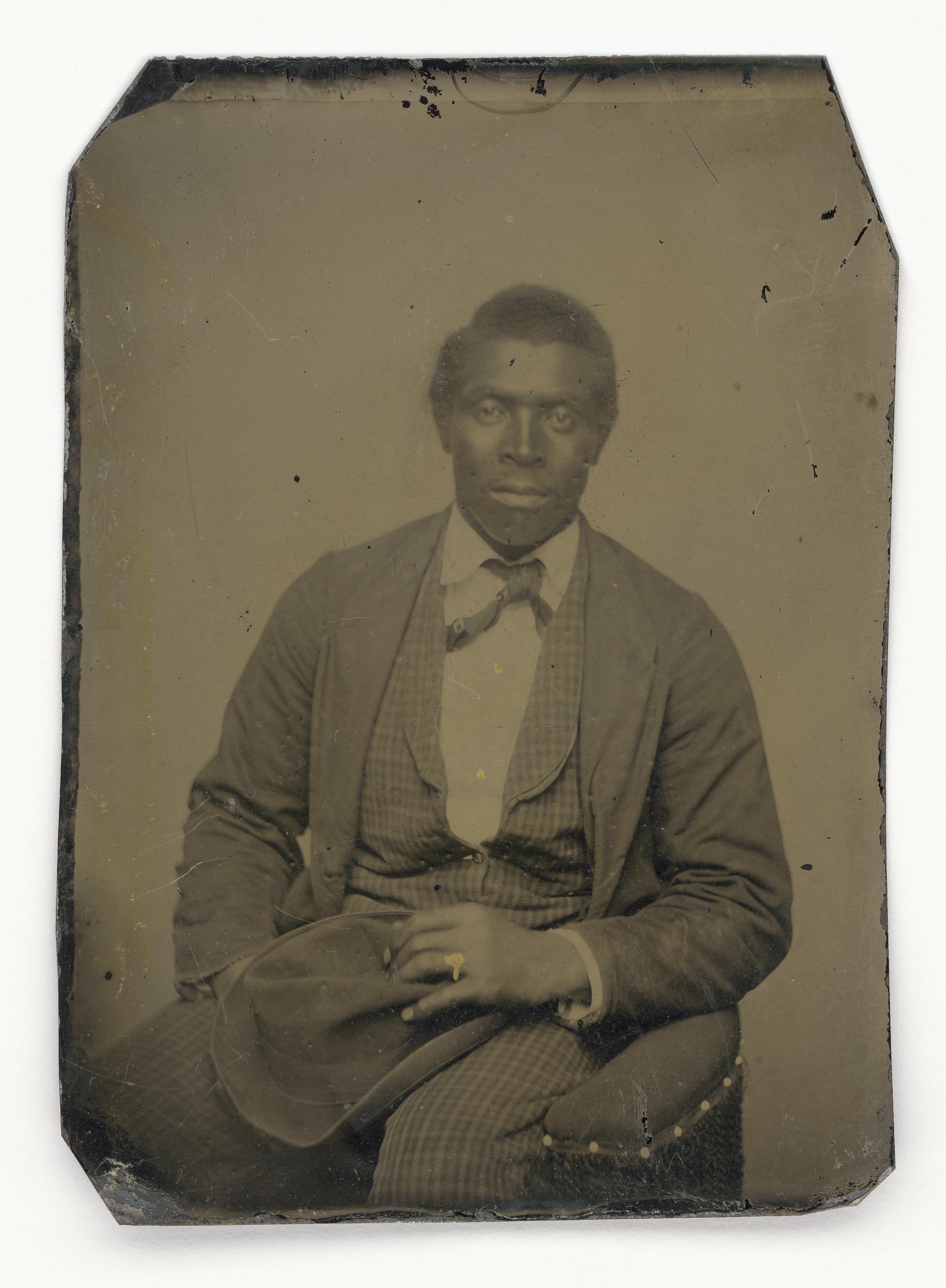 Public-domain Smithsonian tintype of an unidentified African American man seated with a hat on his lap